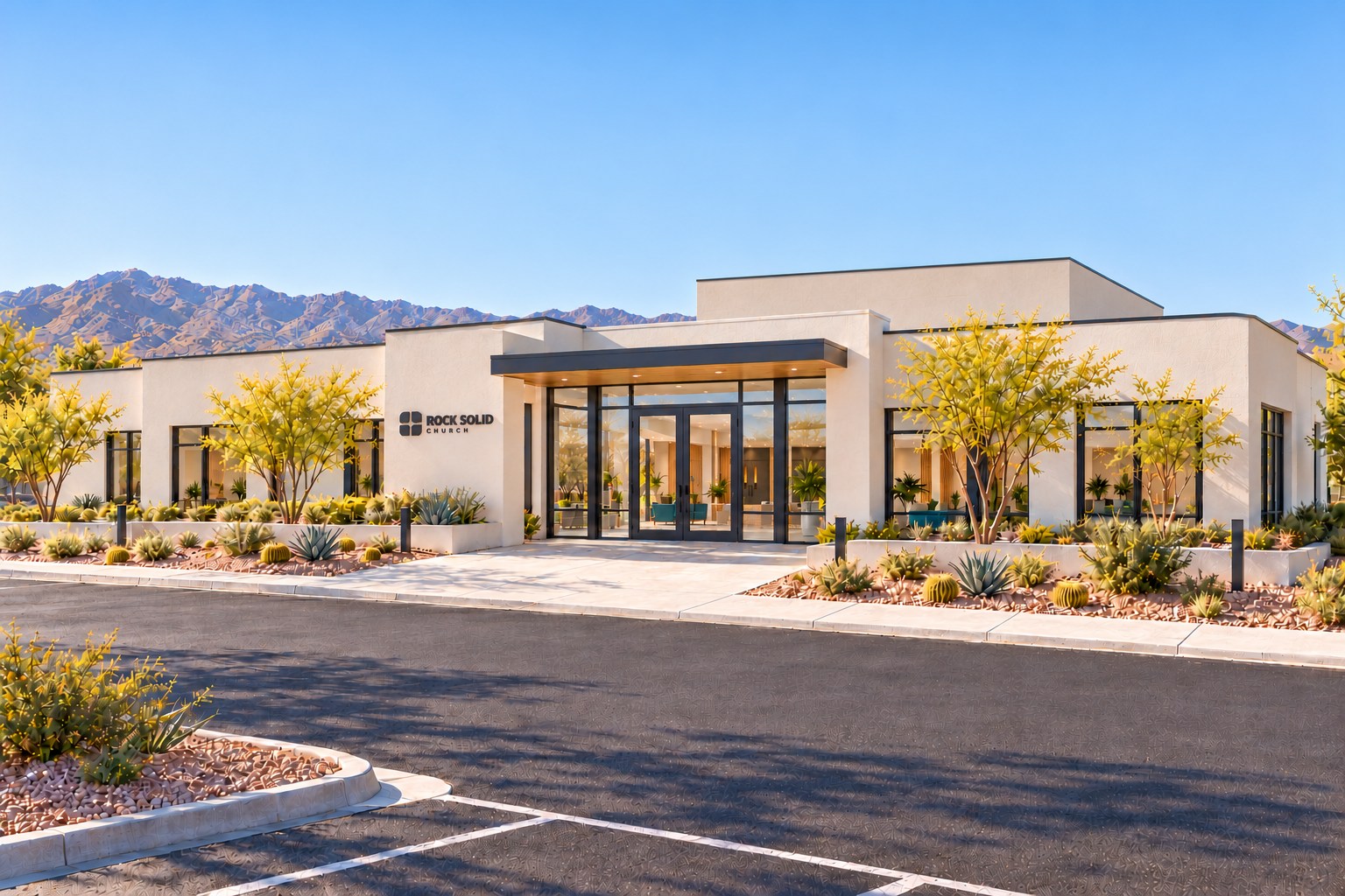 The front of Rock Solid Church: a low, warm-white building with a charcoal canopy, glass doors, and desert landscaping.